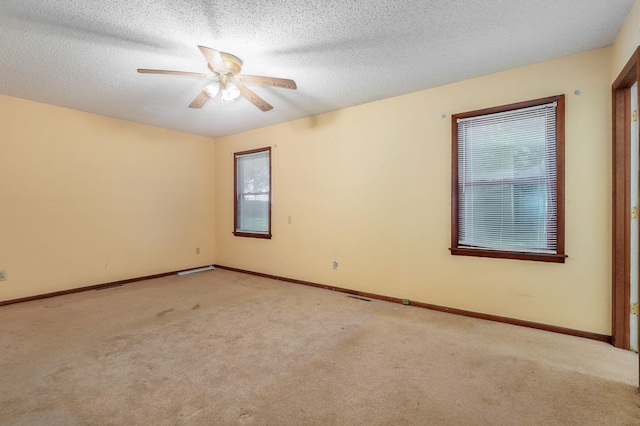 empty room with ceiling fan, light colored carpet, and a textured ceiling