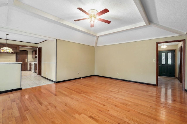 spare room featuring a raised ceiling, ceiling fan, a textured ceiling, and light hardwood / wood-style floors