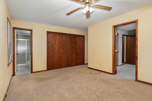 unfurnished bedroom featuring ensuite bathroom, ceiling fan, light carpet, a textured ceiling, and a closet