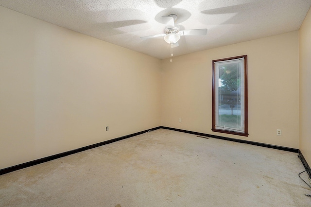 empty room with ceiling fan, light colored carpet, and a textured ceiling