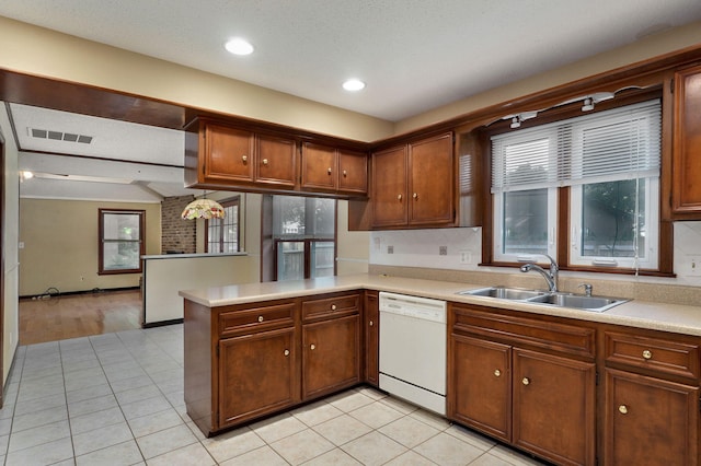 kitchen with sink, light tile patterned floors, kitchen peninsula, and dishwasher