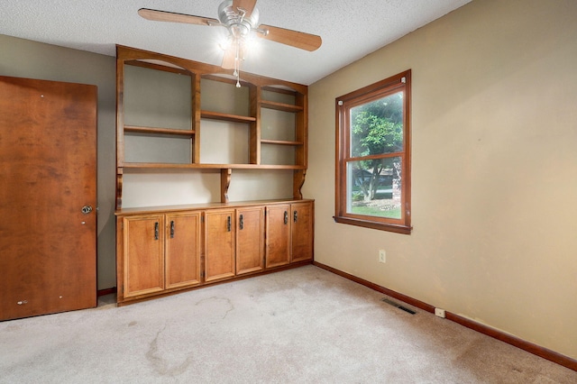 carpeted spare room featuring ceiling fan and a textured ceiling