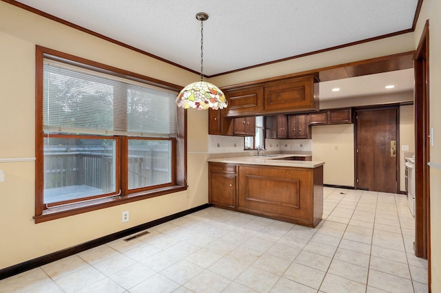 kitchen featuring pendant lighting, sink, ornamental molding, kitchen peninsula, and a textured ceiling