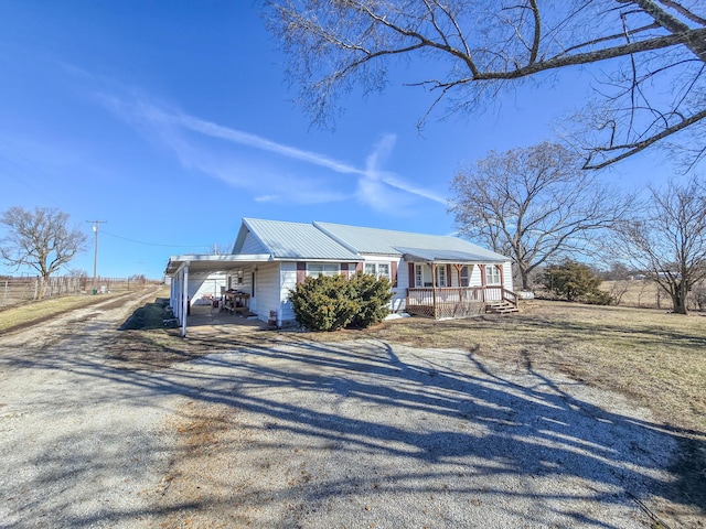 view of front of house with metal roof, a carport, covered porch, and gravel driveway