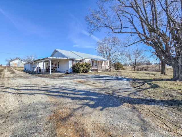 view of front of home with a porch and gravel driveway