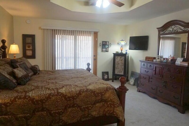 carpeted bedroom featuring a raised ceiling and ceiling fan