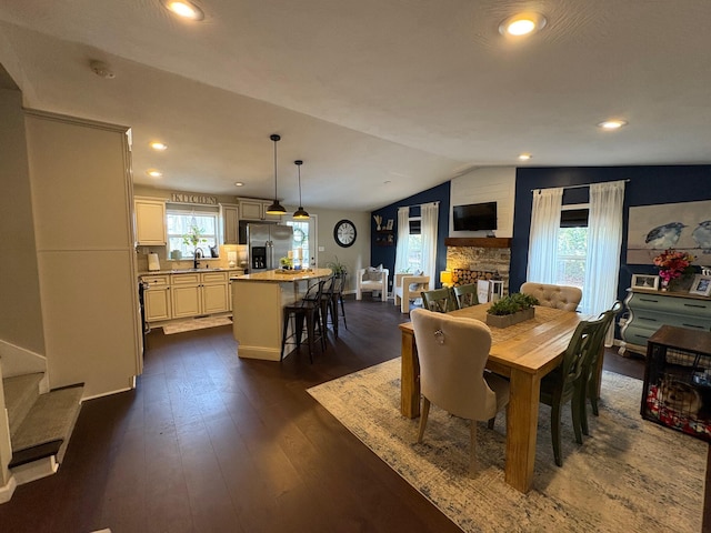 dining room featuring a fireplace, lofted ceiling, dark hardwood / wood-style flooring, and sink