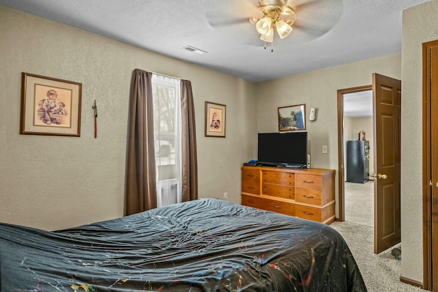 carpeted bedroom featuring ceiling fan and a textured ceiling