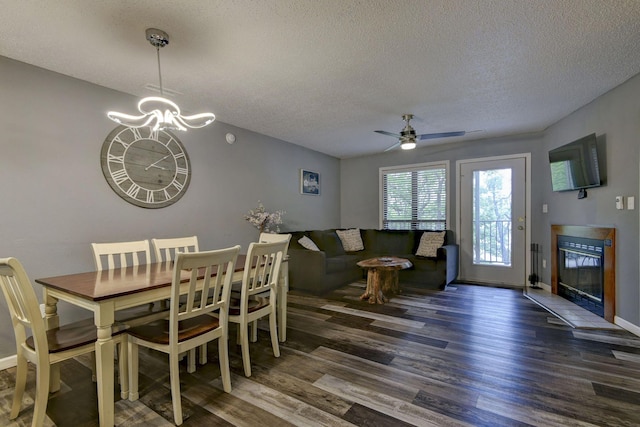 dining room featuring ceiling fan with notable chandelier, a textured ceiling, and dark hardwood / wood-style flooring