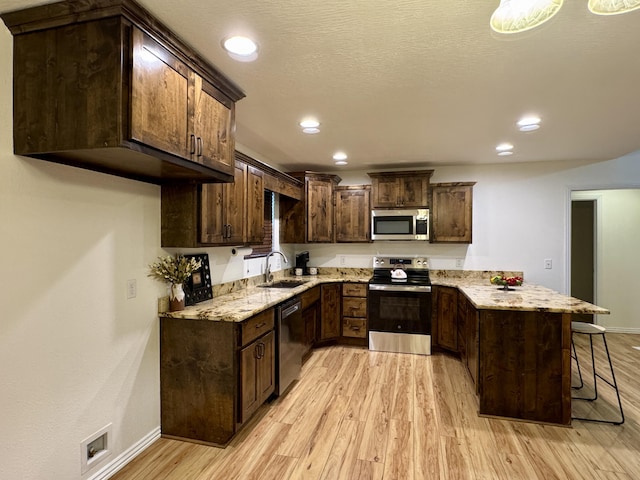 kitchen with dark brown cabinetry, stainless steel appliances, sink, and a breakfast bar area