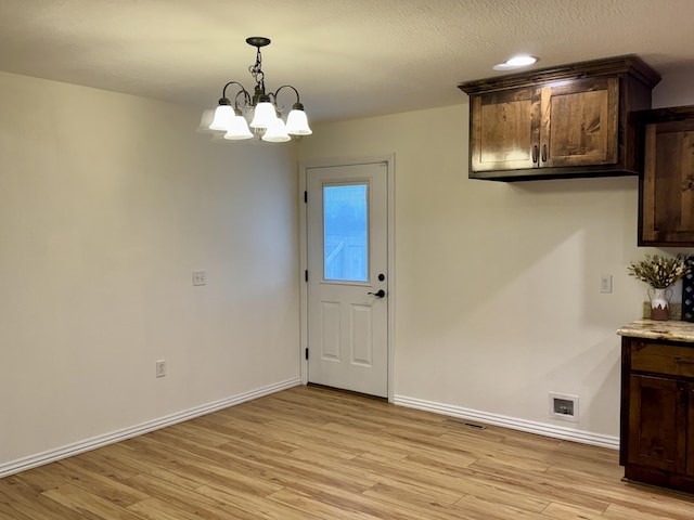 unfurnished dining area featuring a notable chandelier and light hardwood / wood-style floors