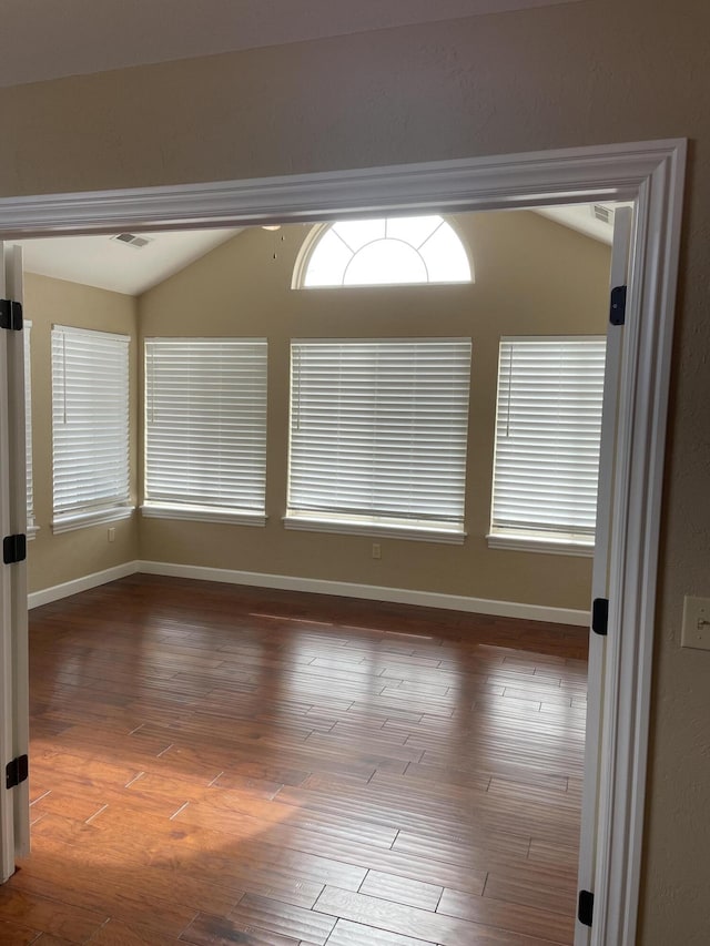 unfurnished room featuring hardwood / wood-style flooring and lofted ceiling