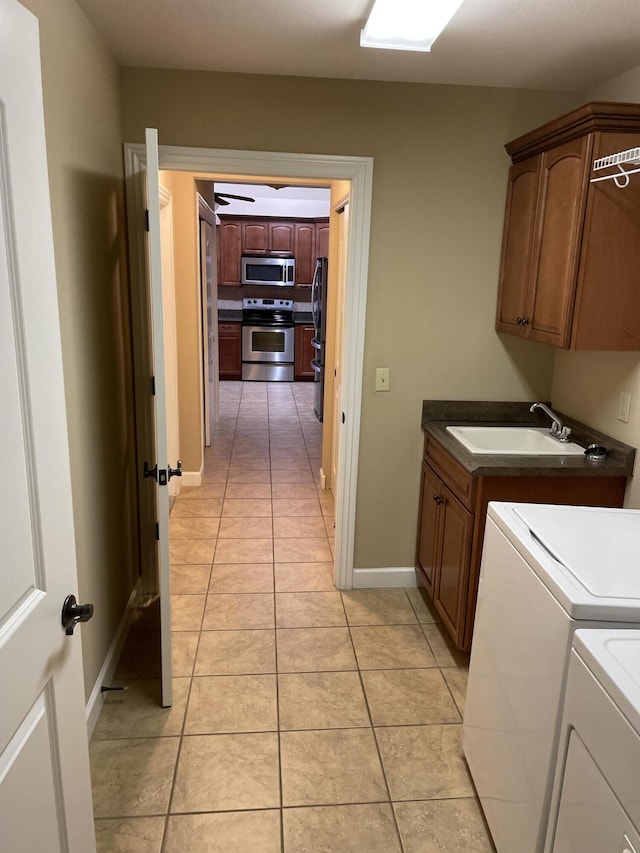 clothes washing area featuring cabinets, sink, washing machine and dryer, and light tile patterned floors