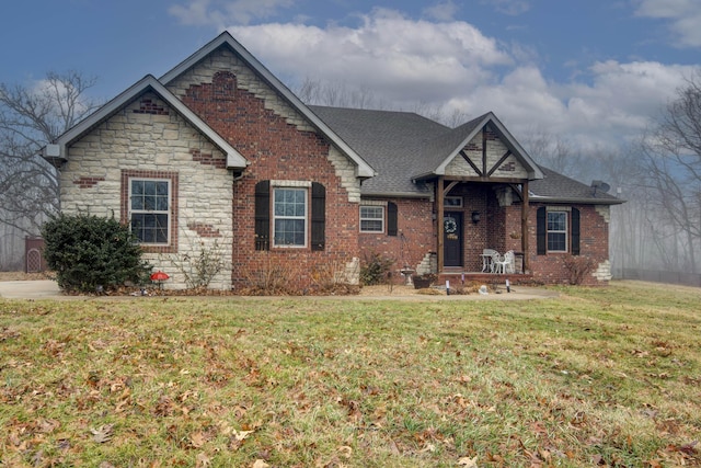 view of front of home featuring brick siding, a front lawn, and a shingled roof
