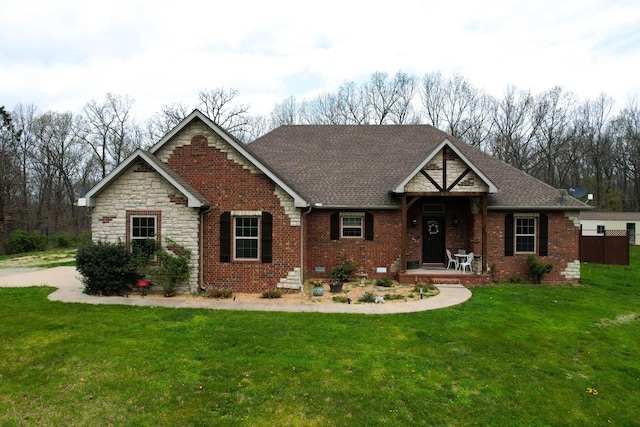view of front of home with brick siding, a front lawn, and roof with shingles