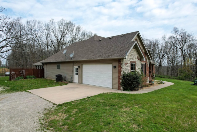 view of side of property with central AC, a lawn, stone siding, an attached garage, and driveway