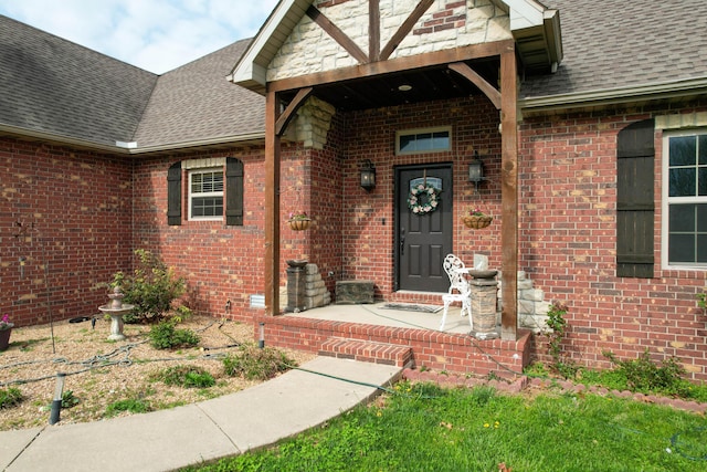 doorway to property featuring brick siding and roof with shingles