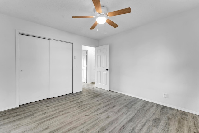 unfurnished bedroom featuring ceiling fan, light hardwood / wood-style floors, and a closet