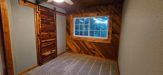 11498 Weatherman Dr, Mountain Grove, MO 65711 - carpeted spare room with wooden walls, a textured wall, a barn door, baseboards, and a ceiling fan