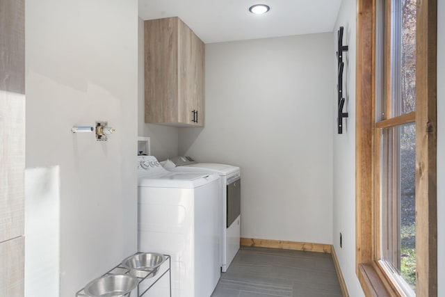 washroom featuring cabinet space, baseboards, and separate washer and dryer