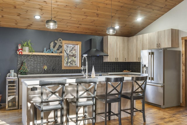 kitchen featuring beverage cooler, high end refrigerator, lofted ceiling, wall chimney exhaust hood, and backsplash