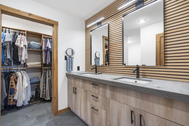 full bathroom with double vanity, a sink, and a walk in closet