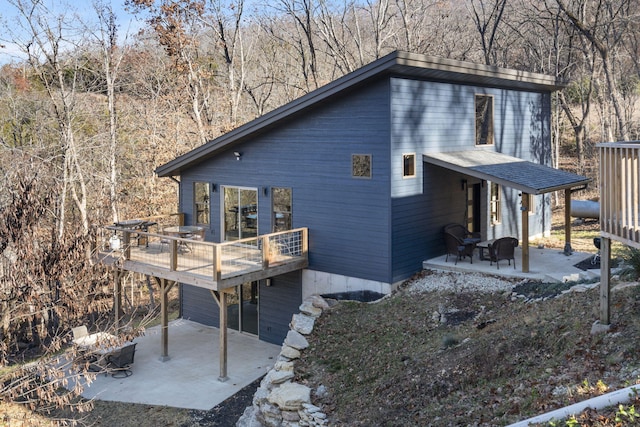 view of side of property with a forest view, a patio area, and a wooden deck