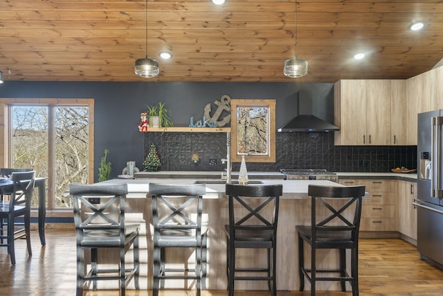 kitchen featuring modern cabinets, wall chimney range hood, high end refrigerator, and light brown cabinetry