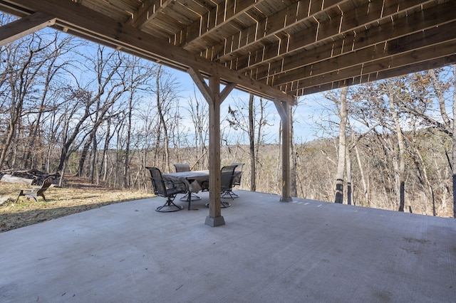 view of patio with outdoor dining space and a wooded view