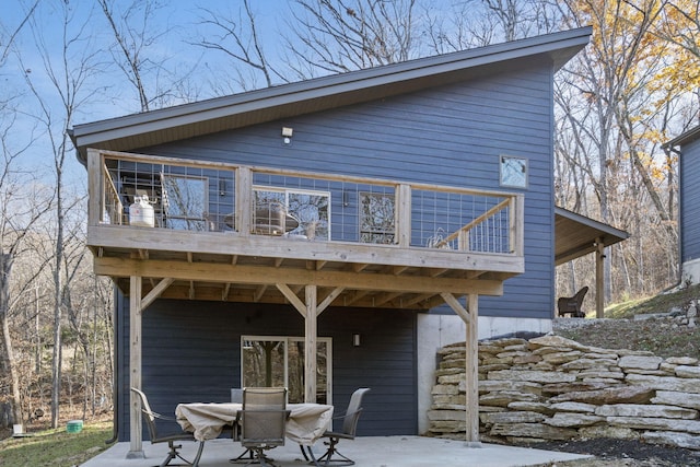 rear view of house featuring a wooden deck and a patio