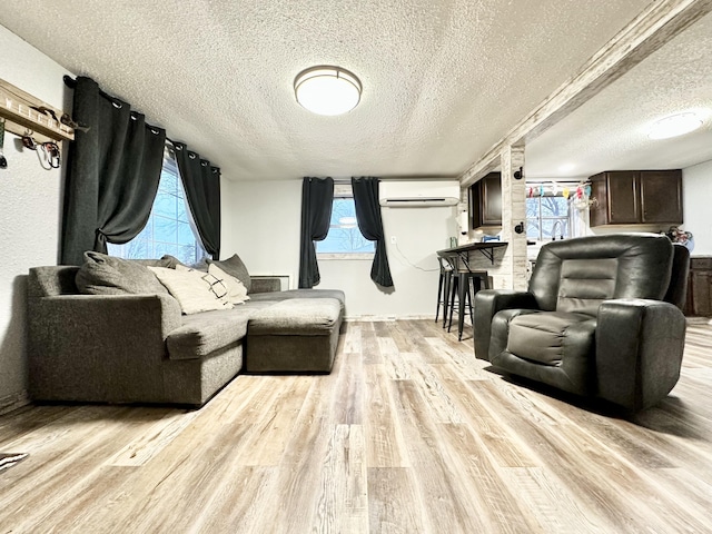 living room featuring light hardwood / wood-style floors, a wall mounted AC, and a textured ceiling