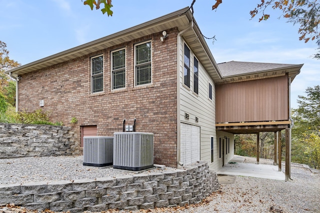 view of side of property featuring a patio area, central AC, and brick siding