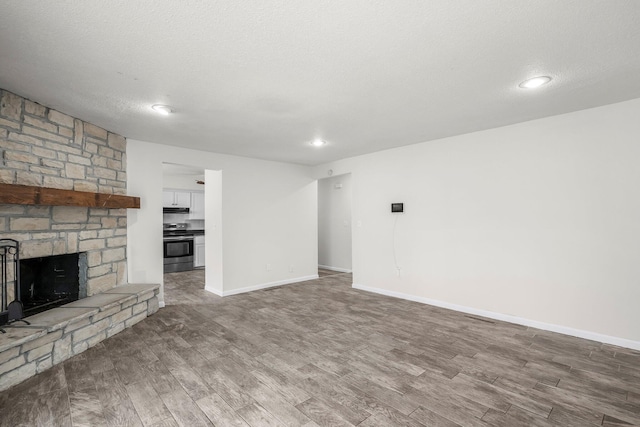 unfurnished living room with wood-type flooring, a textured ceiling, and a fireplace