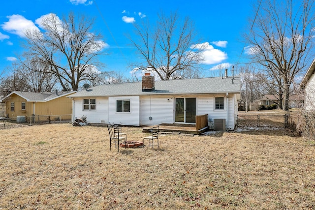 rear view of property with cooling unit, a yard, and a fire pit