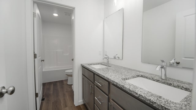 full bathroom with toilet, hardwood / wood-style flooring,  shower combination, and vanity