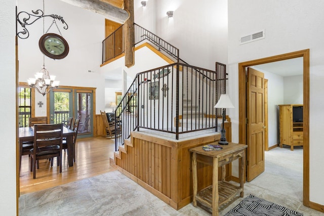 stairs with a high ceiling, a notable chandelier, and wood-type flooring