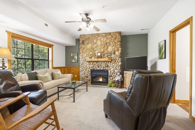 living room with ceiling fan, light colored carpet, and a stone fireplace