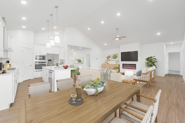 dining area featuring sink, high vaulted ceiling, ceiling fan, and light hardwood / wood-style flooring