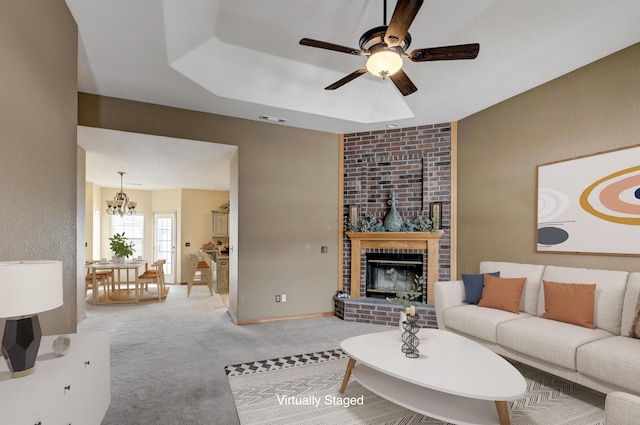 living room featuring a fireplace, ceiling fan with notable chandelier, and light colored carpet