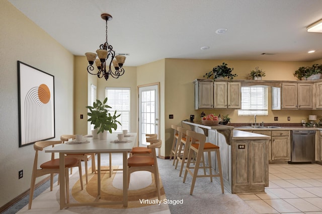 kitchen with stainless steel dishwasher, sink, a kitchen bar, and light brown cabinets