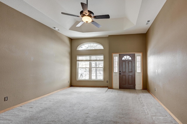 carpeted foyer entrance with a tray ceiling and ceiling fan