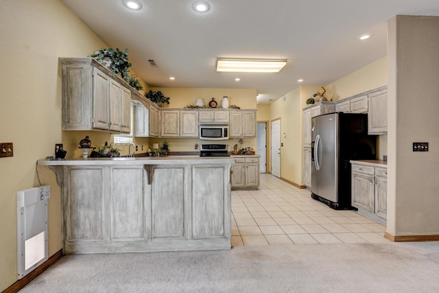 kitchen with a kitchen bar, appliances with stainless steel finishes, sink, light tile patterned floors, and kitchen peninsula