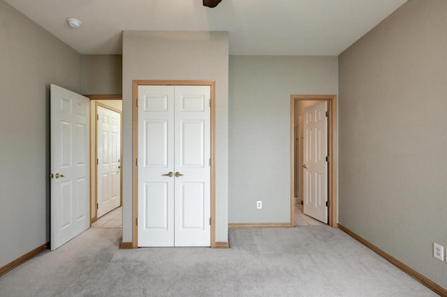 unfurnished bedroom featuring light carpet, ceiling fan, and a closet