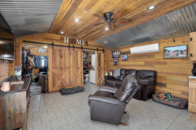 living room with lofted ceiling, a wall mounted air conditioner, a barn door, wood walls, and ceiling fan