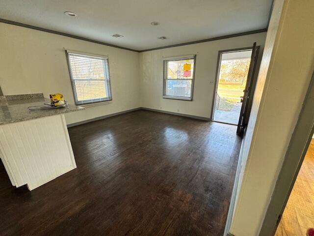 unfurnished dining area featuring dark wood-type flooring and crown molding