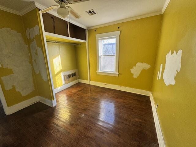 unfurnished bedroom with a closet, a wall unit AC, dark hardwood / wood-style floors, ceiling fan, and crown molding