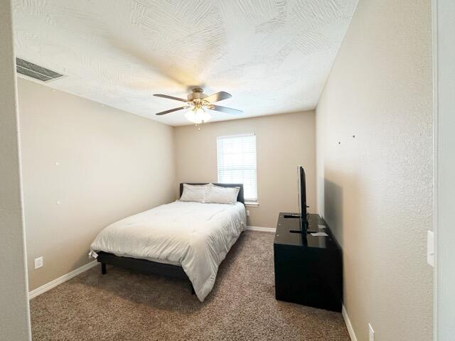 carpeted bedroom featuring ceiling fan and a textured ceiling