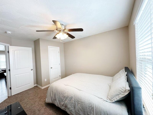 carpeted bedroom featuring multiple windows and ceiling fan