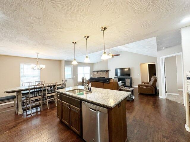 kitchen featuring dishwasher, dark wood-type flooring, decorative light fixtures, sink, and a kitchen island with sink