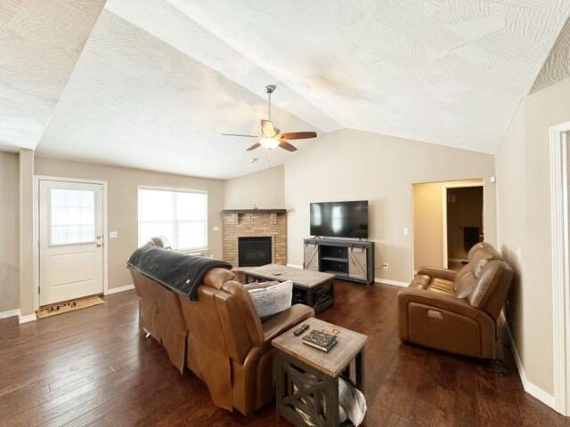 living room with a fireplace, lofted ceiling, dark hardwood / wood-style flooring, ceiling fan, and a textured ceiling